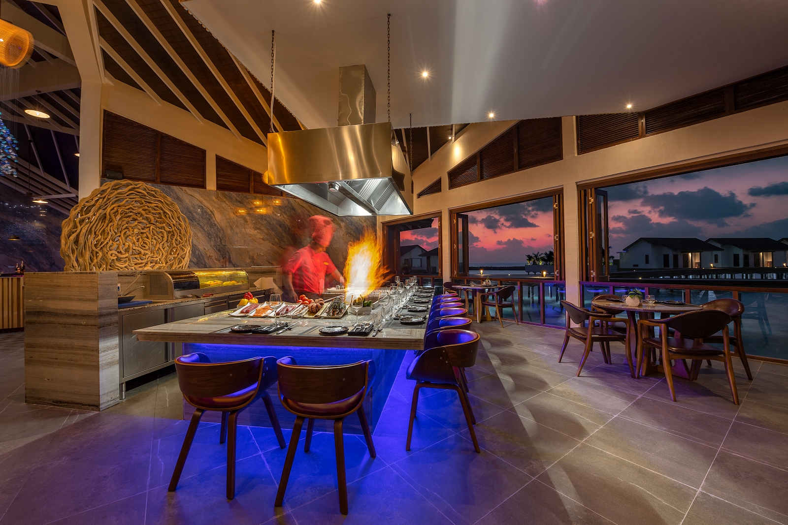 Cook preparing food at a teppanyaki bar at Pier Six restaurant at luxury resort Atmosphere Kanifushi in the Maldives
