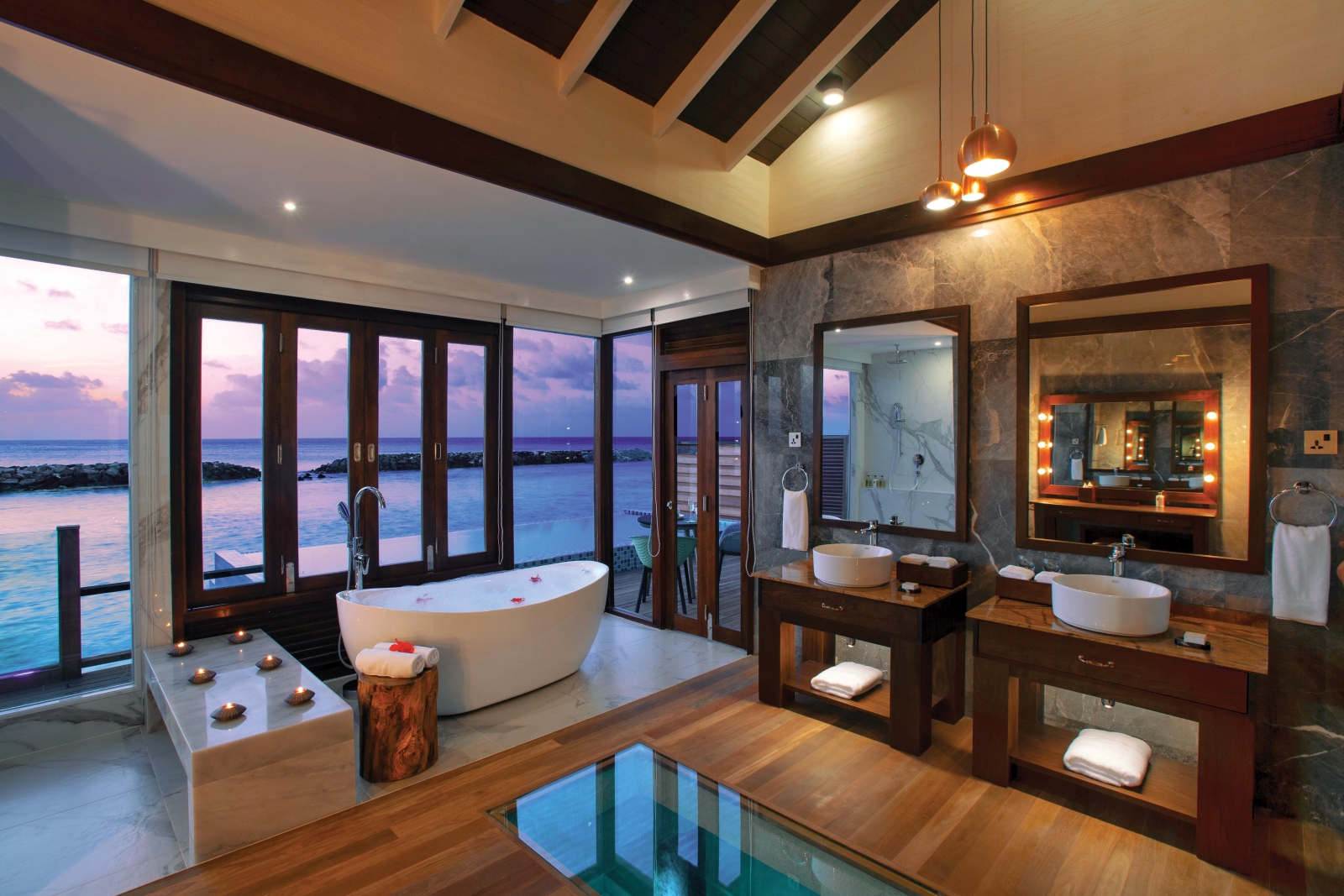 Bathroom of a Water Villa with pool, with double vanity and bathtub with sliding doors at luxury resort Atmosphere Kanifushi in the Maldives