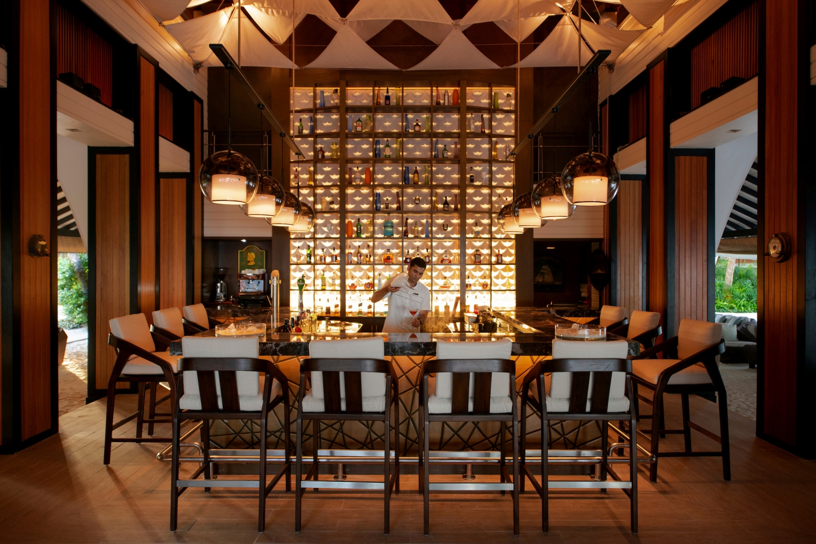 Bar seating and barman at Sails Bar at Baros