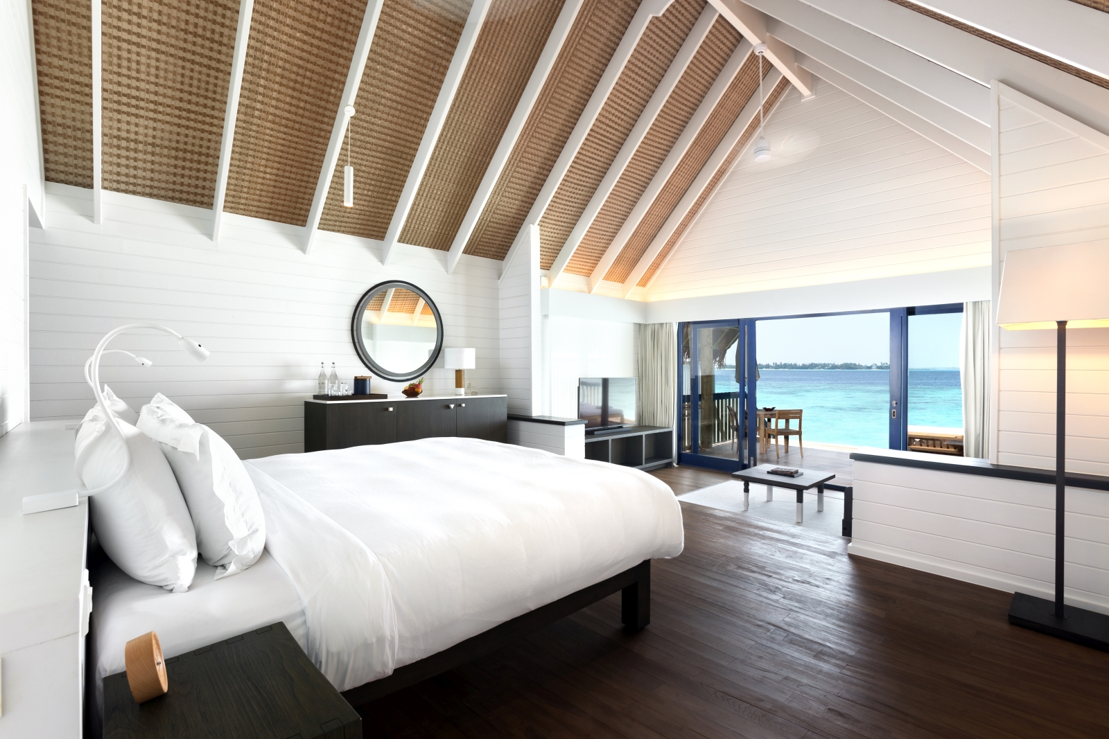 Interior of a Dhoni Water Villa with bedroom and living area as well as private deck at luxury resort Cocoa Island in the Maldives