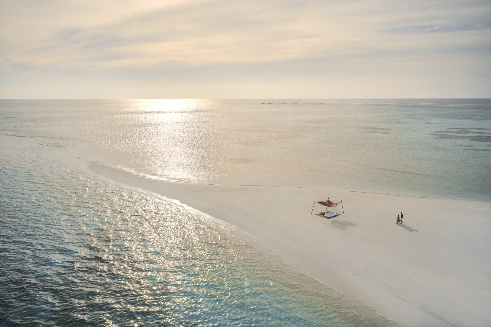 Couple walking along a sandbank at luxury resort Cocoa Island in the Maldives