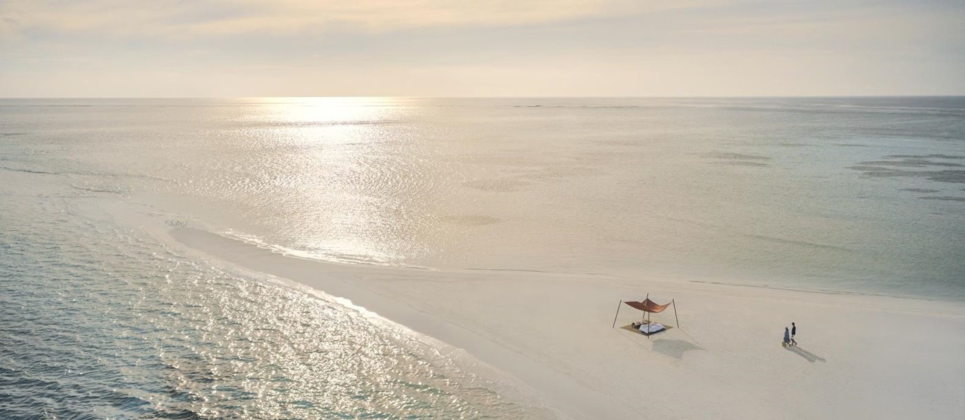 Couple walking along a sandbank at luxury resort Cocoa Island in the Maldives