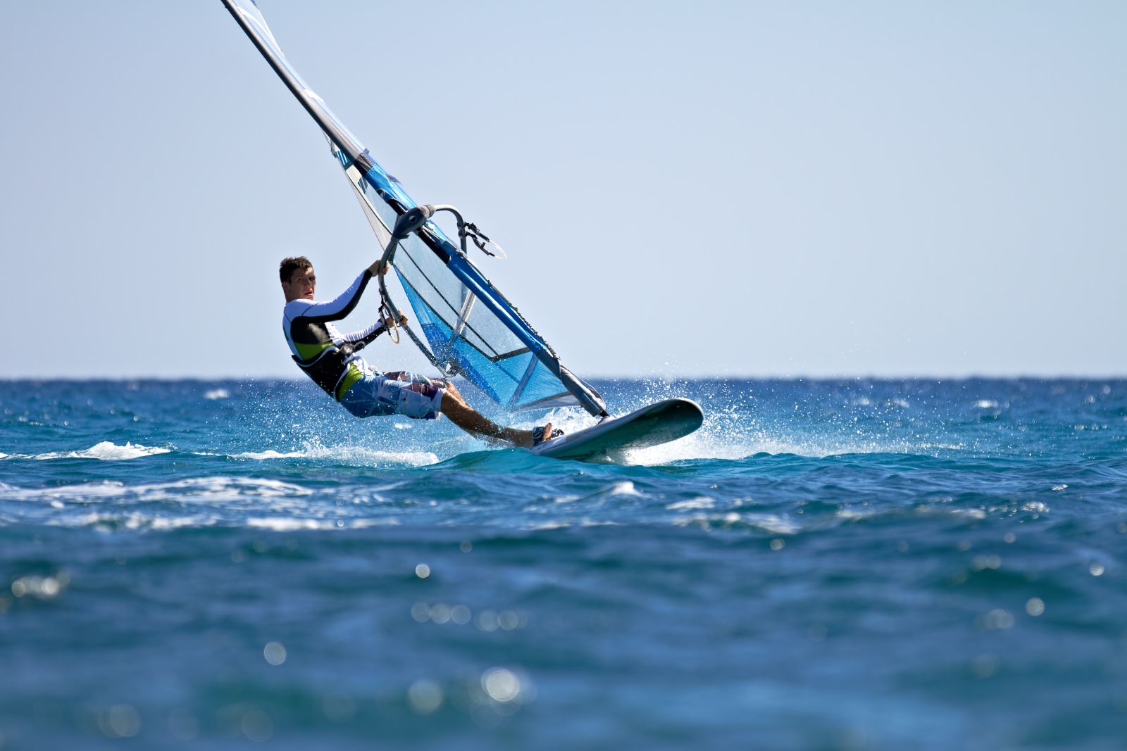 Man windsurfing at luxury resort Cocoa Island in the Maldives
