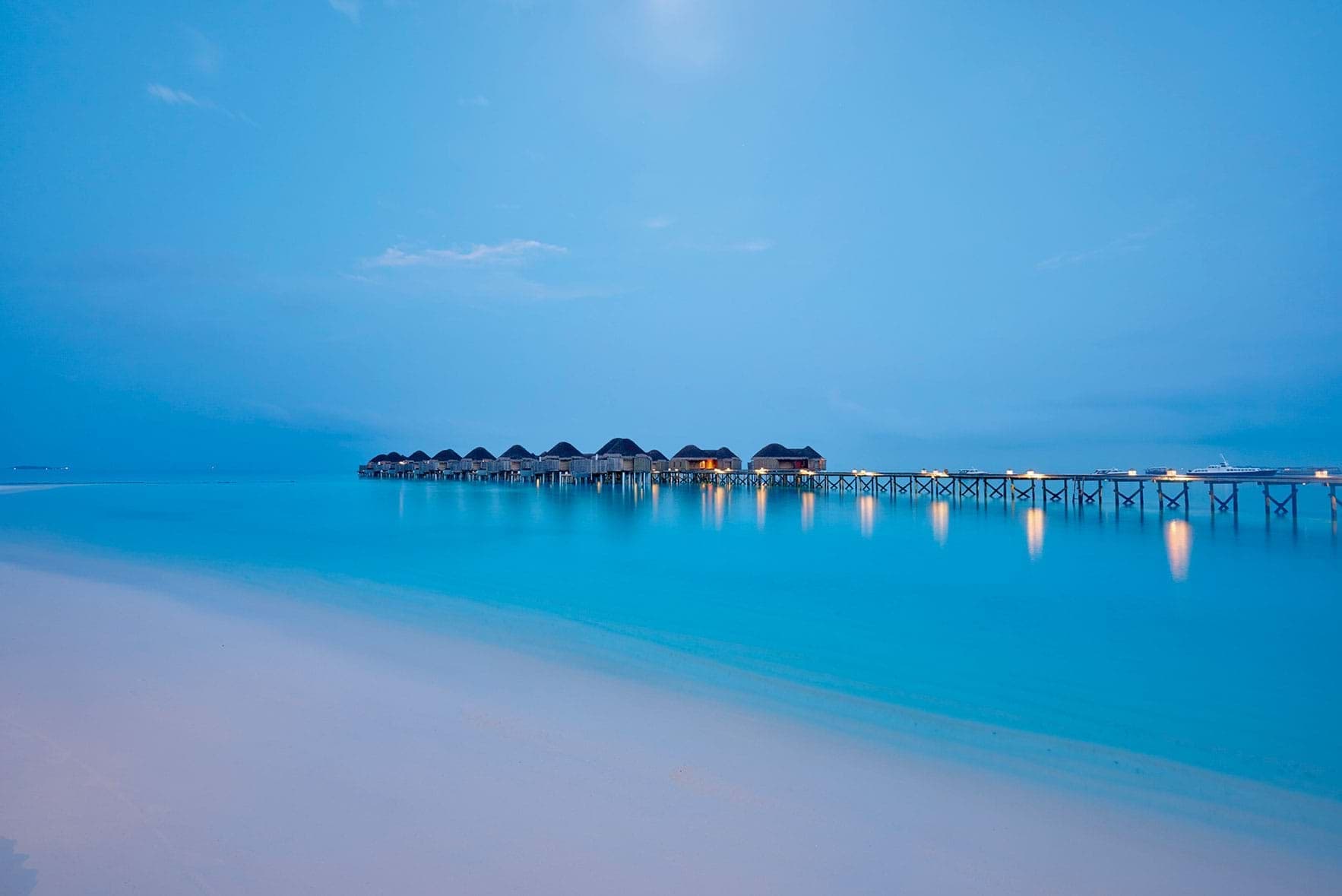 Pristine beach and jetty in the distance at Constance Halaveli Maldives