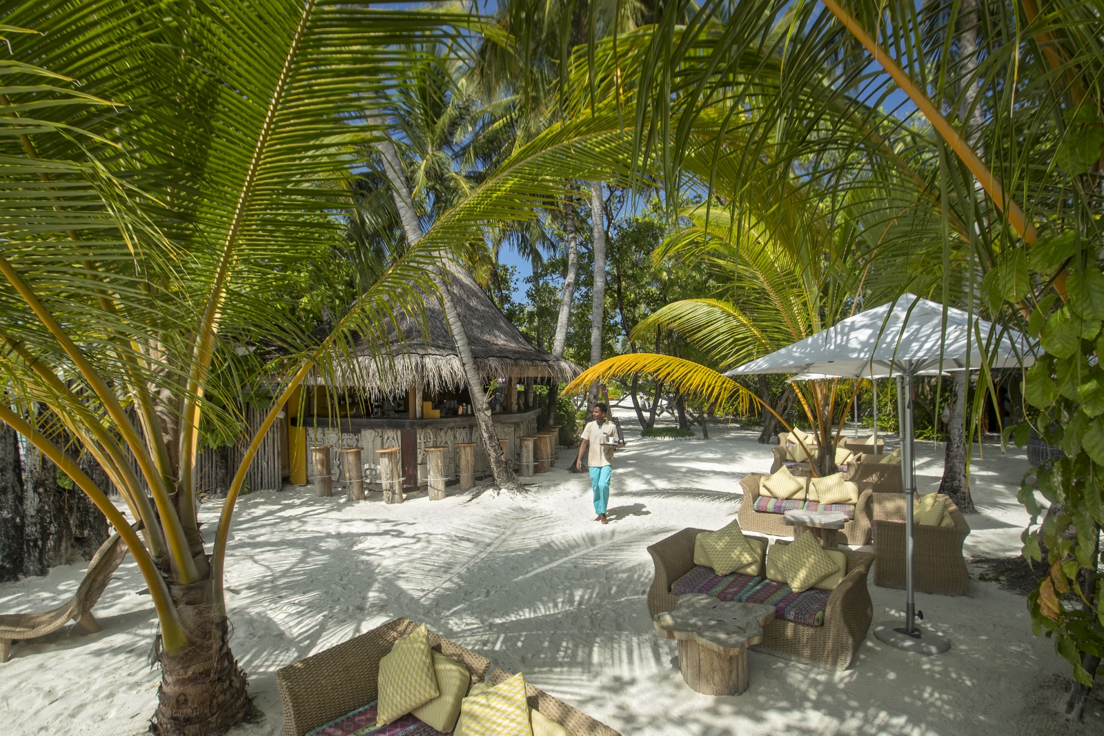 Waiter with drinks at Totem Bar at luxury resort Constance Moofushi in the Maldives