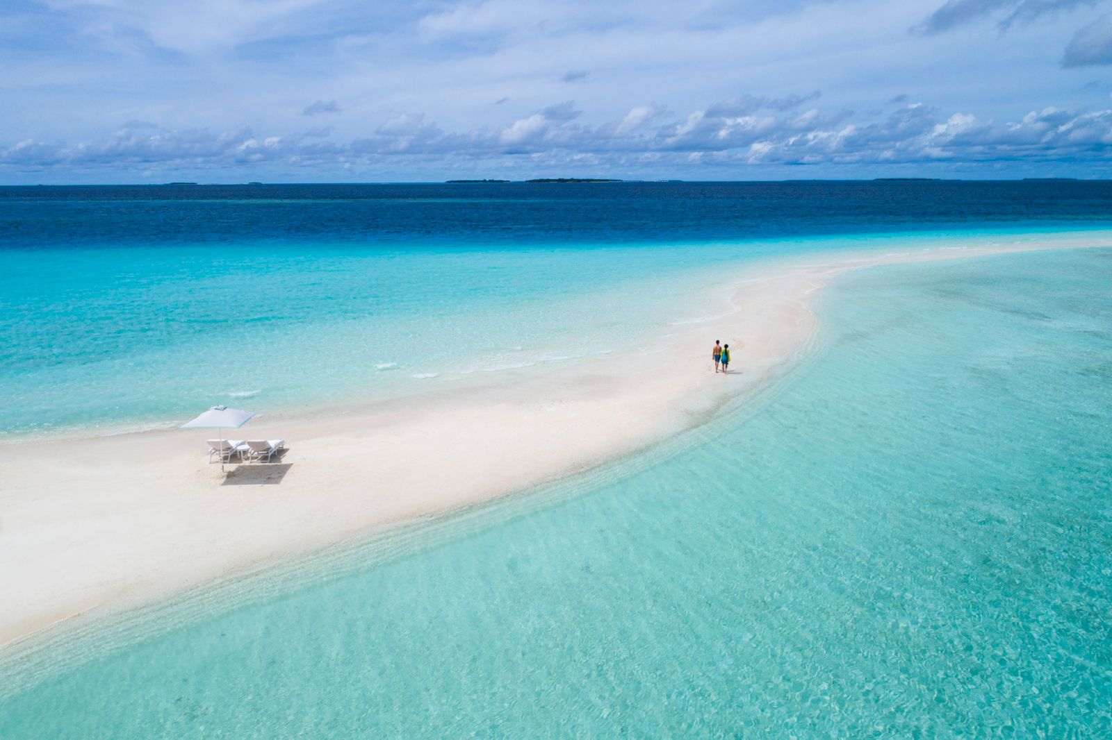 Couple walking along deserted sandbank at the Four Seasons Landaa Giraavaru in the Maldives