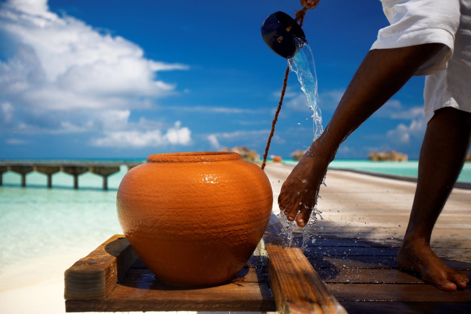 Man washing sand off his feet at luxury resort Gili Lankanfushi in the Maldives
