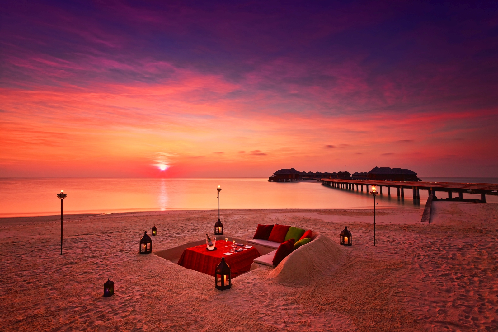 Private beach dining setup at sunset at luxury resort Huvafen Fushi in the Maldives