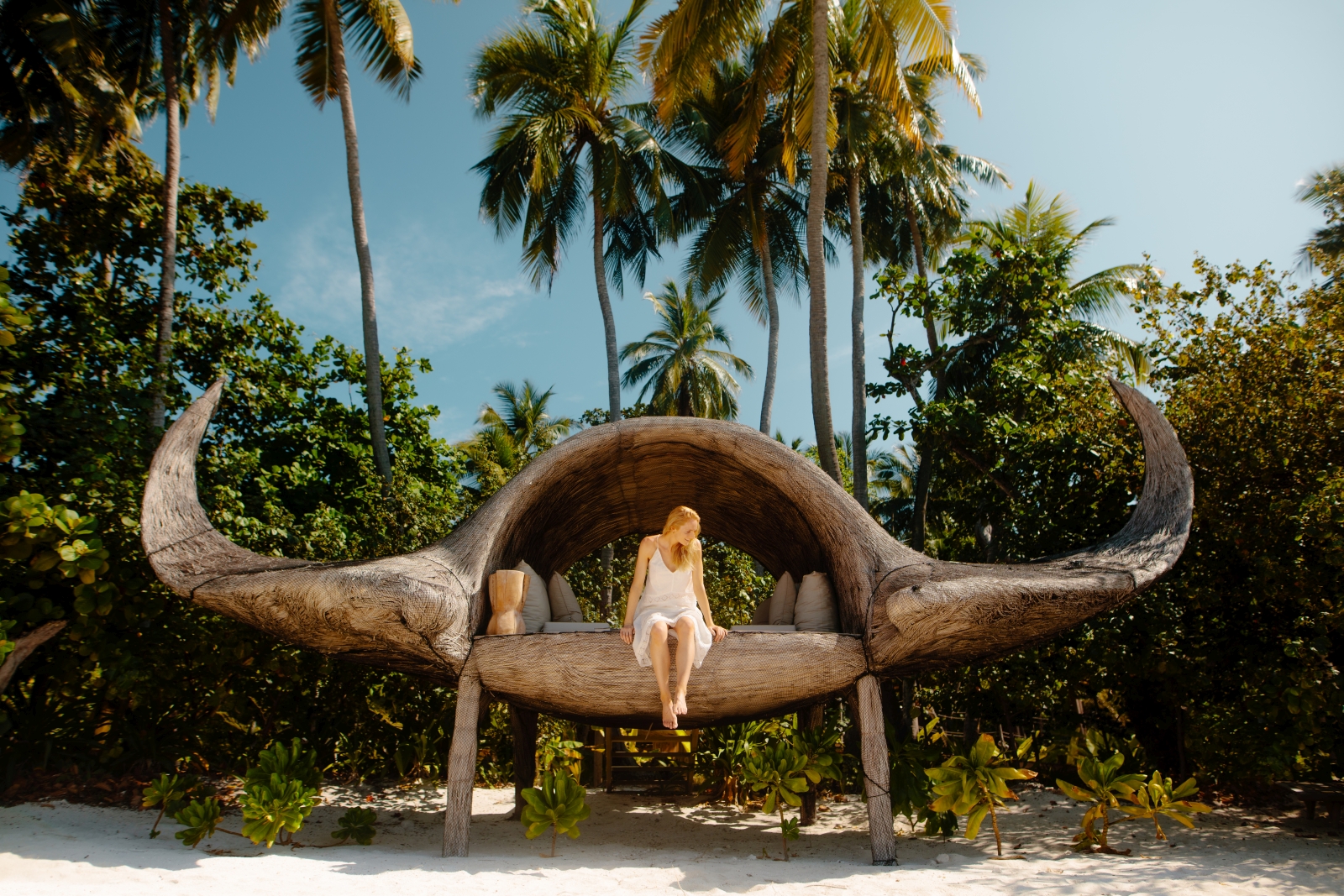 Woman sitting on an art installation which looks to be inspired by buffalo horns at luxury resort Joali in the Maldives