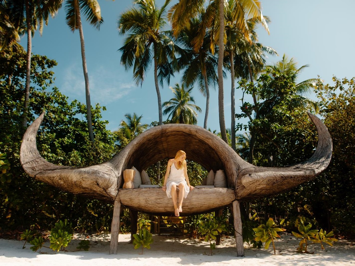 Woman sitting on an art installation which looks to be inspired by buffalo horns at luxury resort Joali in the Maldives