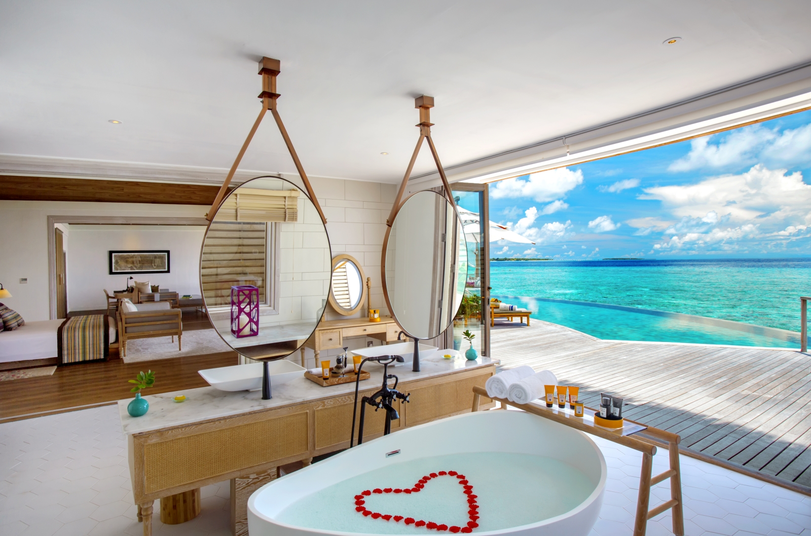 Interior of an Ocean REsidence with open plan bathroom and bedroom, private terrace and pool and the turquoise Indian Ocean luxury resort Milaidhoo in the Maldives