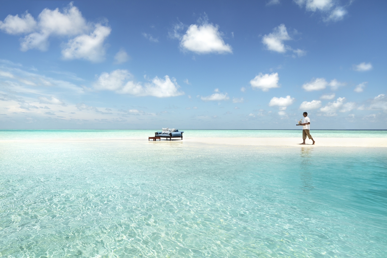 Butler serving drinks on a sandbank at luxury resort Naladhu in the Maldives