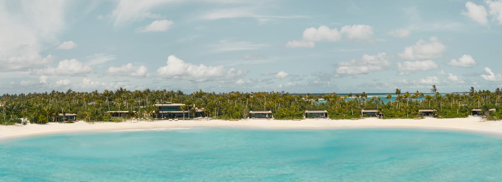View of the beach and beach villas at luxury resort Patina in the Maldives