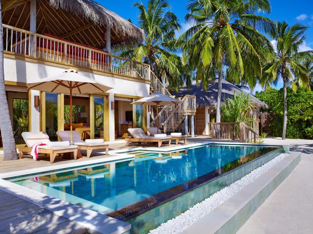 The terrace of a Two-Bedroom Ocean Beach Villa with private pool, loungers and parasols on the palm-strewn white sand beach of luxury resort Six Senses Laamu in the Maldives