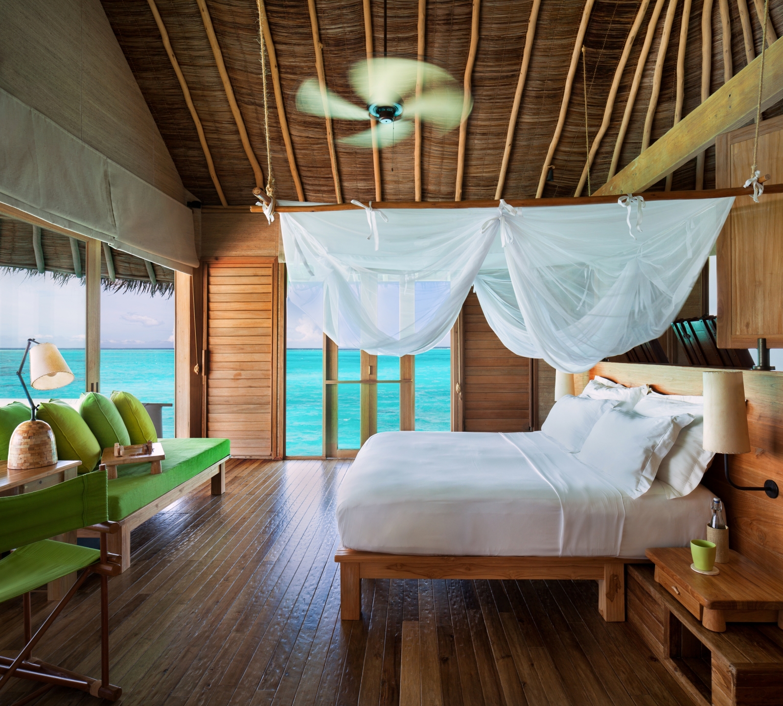Interior of a Water Villa with pool, with double bed, mosquito net and fan, at luxury resort Six Senses Laamu in the Maldives
