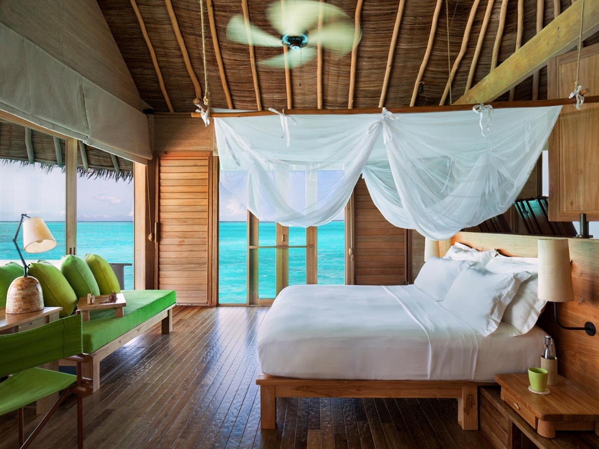 Interior of a Water Villa with pool, with double bed, mosquito net and fan, at luxury resort Six Senses Laamu in the Maldives