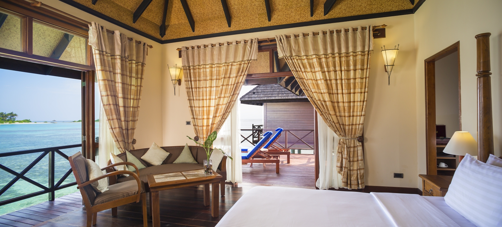 Interior of a Deluxe Water Villa with seating area and private terrace at luxury resort Sun Siyam Olhuveli in the Maldives