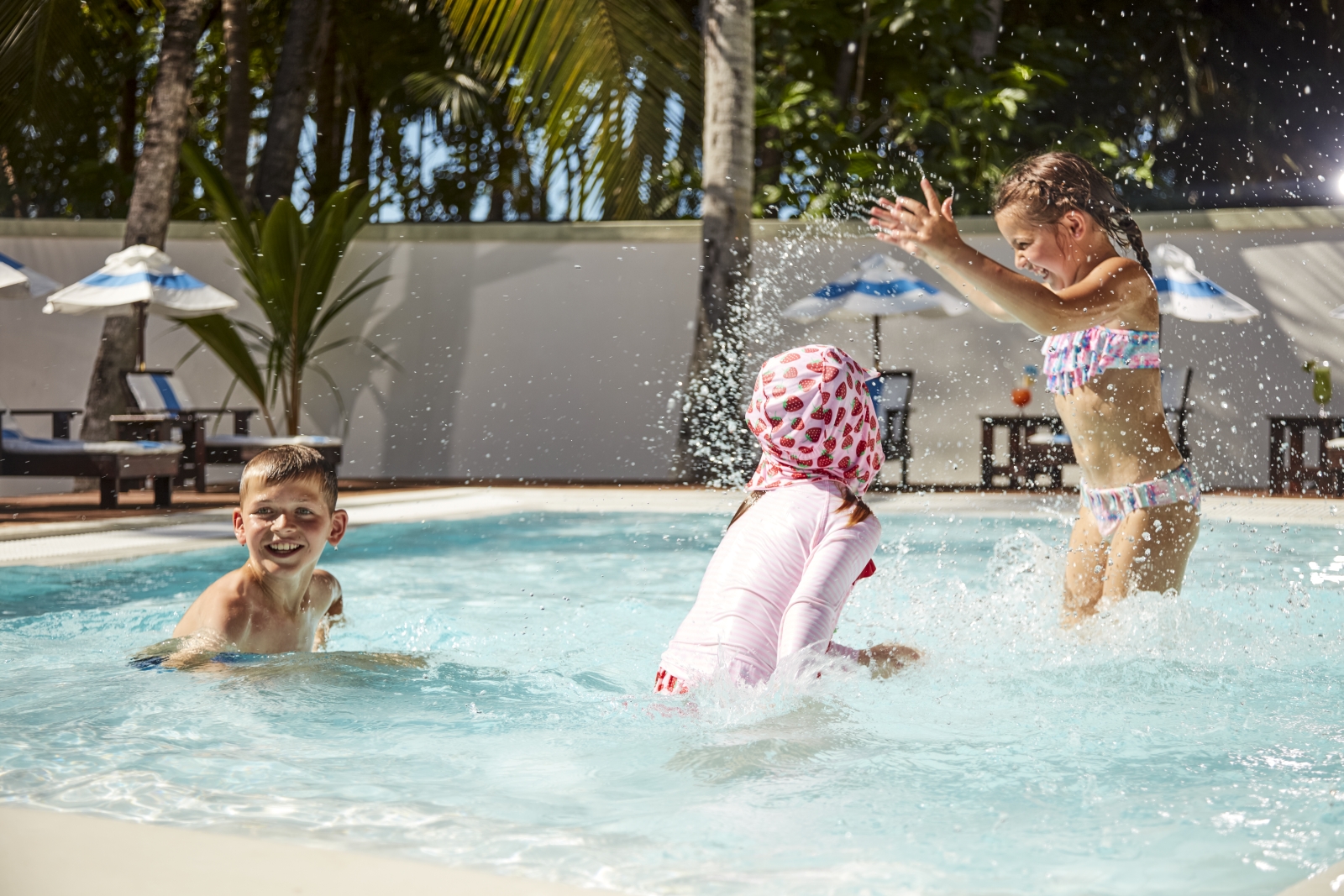 Three children playing in the Kid's Pool at luxury resort Sun Siyam Olhuveli in the Maldives