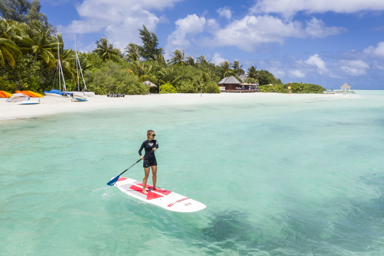 Woman enjoying stand up paddling in the Indian Ocean at luxury resort Sun Siyam Olhuveli in the Maldives