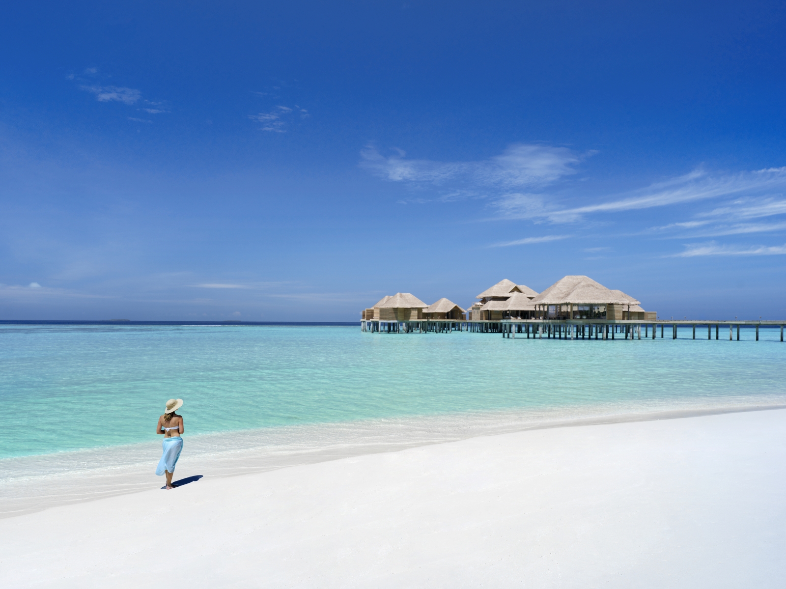Woman walking on the white sand beach at luxury resort Vakkaru in the Maldives