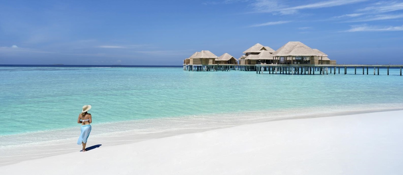 Woman walking on the white sand beach at luxury resort Vakkaru in the Maldives