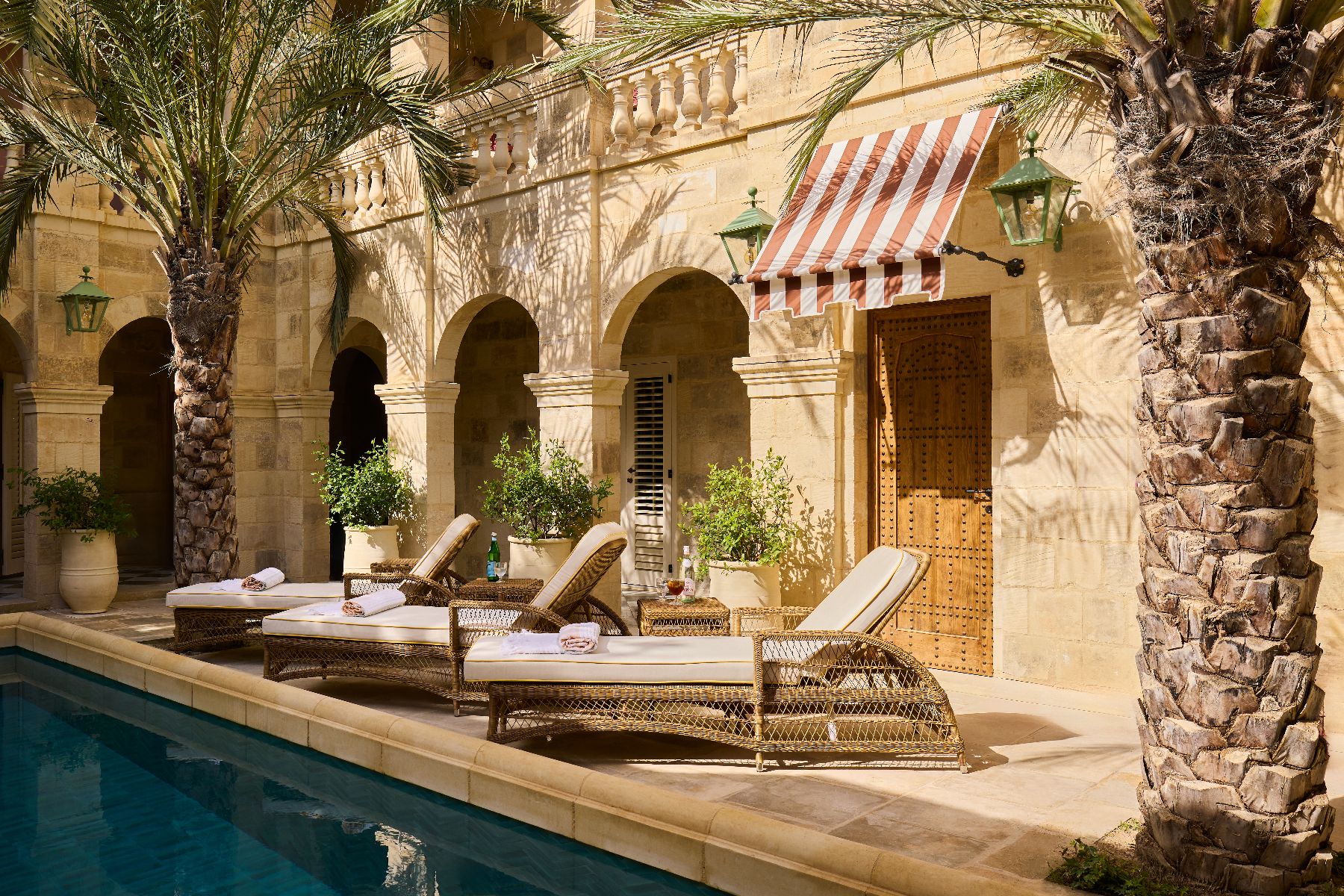 Loungers and palm trees by the pool at Casa Bonavita hotel in Attard Malta