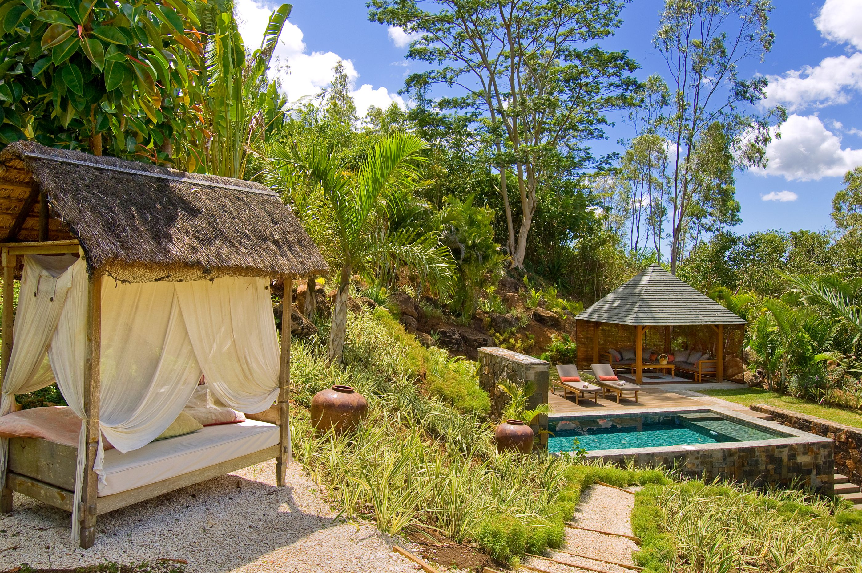 Sun lounger with swimming pool in the background of Lakaz Chamarel, Mauritius