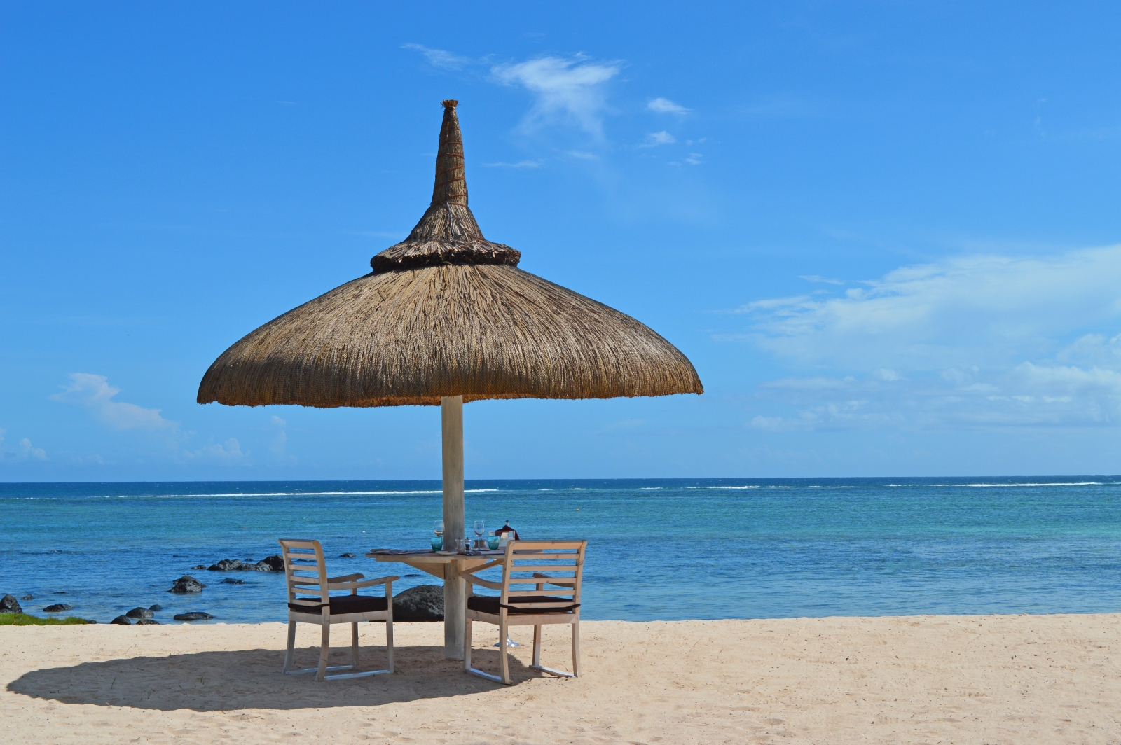 Two chairs under a beach umbrella on a white sand beach