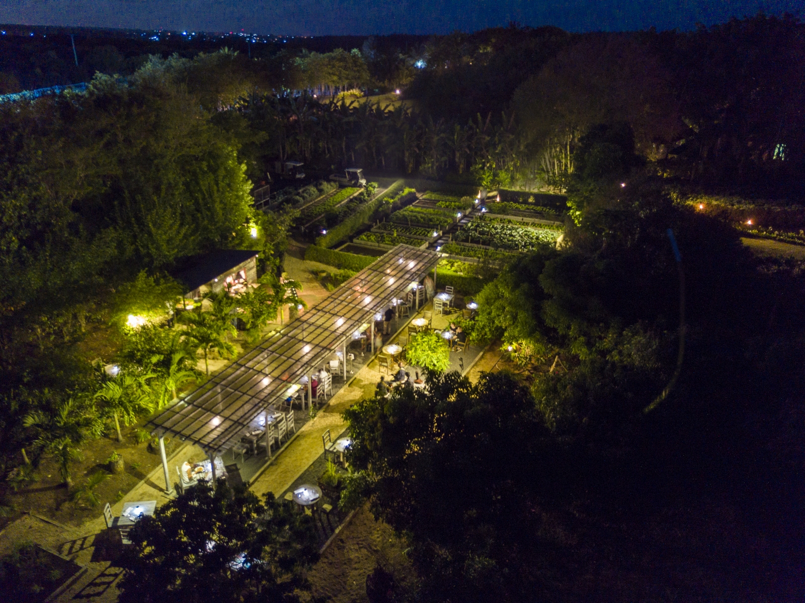 Aerial of the illuminated, open air La Kaze Mama restaurant, set in the herb gardens of Shanti Maurice