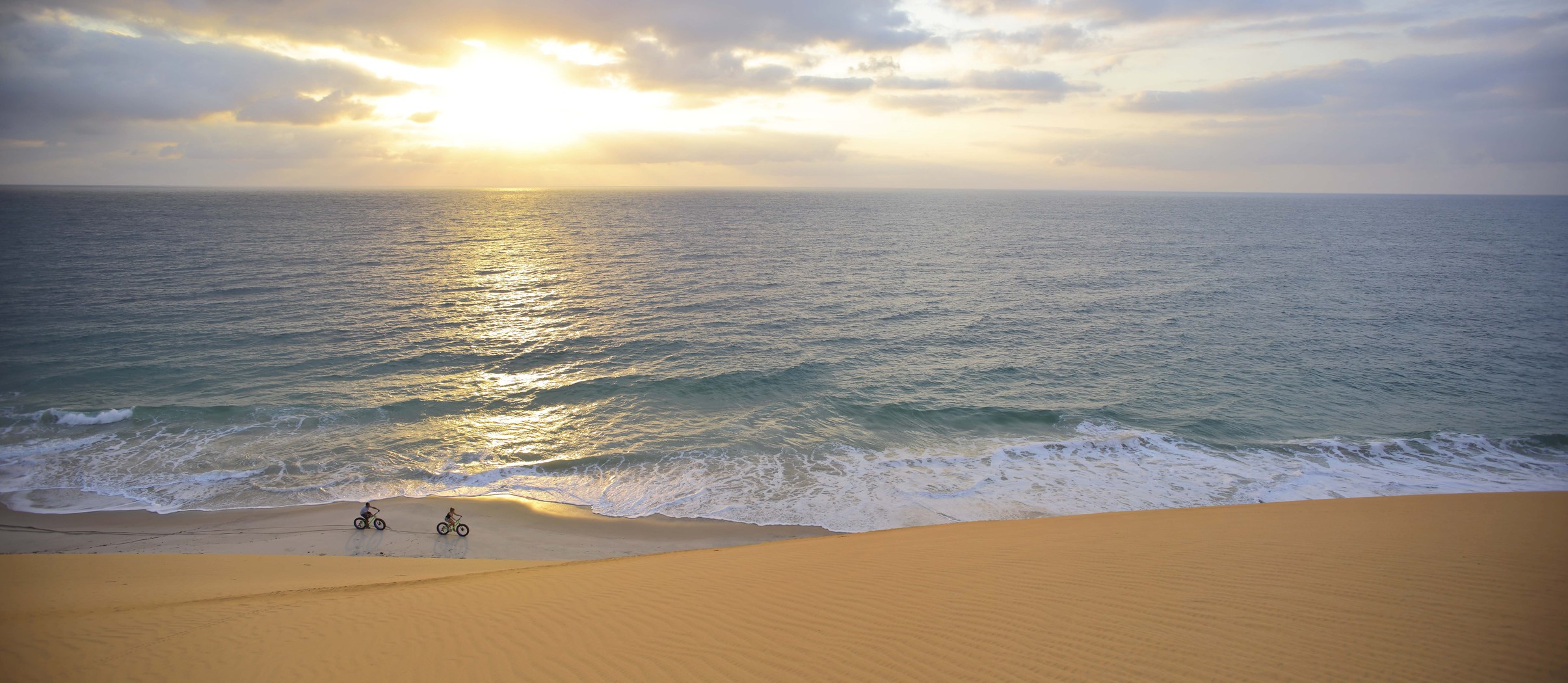 Two people cycling at the beach during sunset at Azura Benguerra, Mozambique
