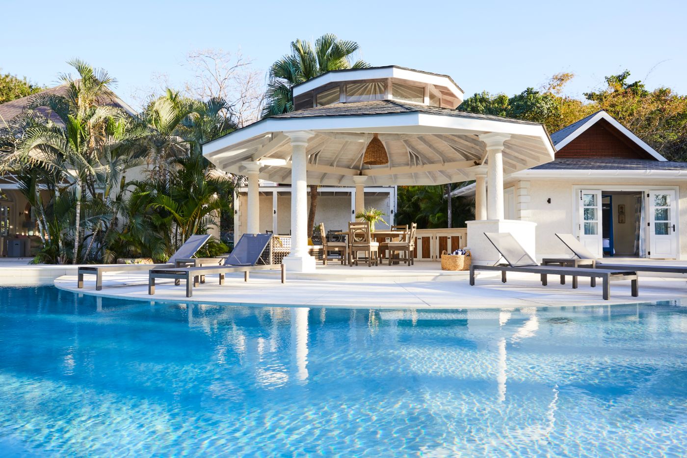 Pool area with loungers and covered outdoor dining terrace at Bamboo House