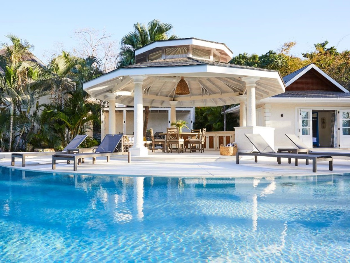 Pool area with loungers and covered outdoor dining terrace at Bamboo House