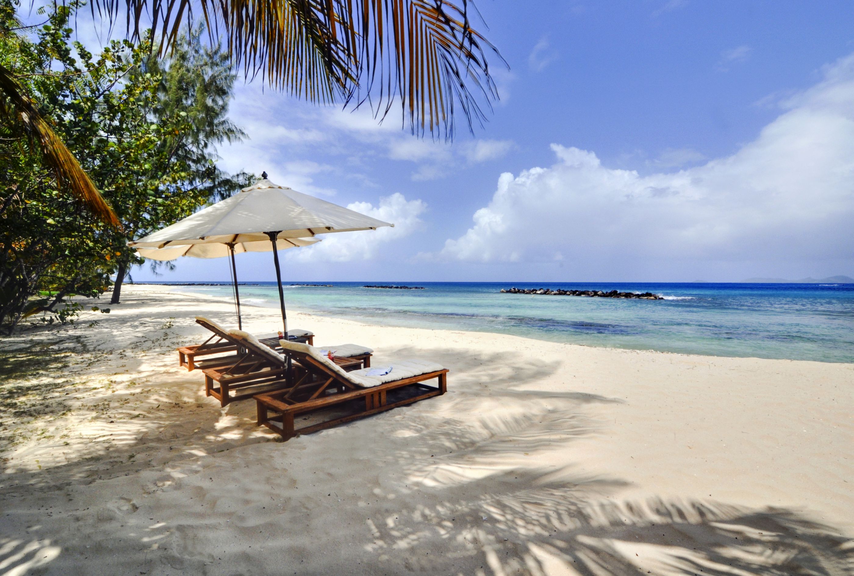 The beach and three sun loungers at Gingerbread, Mustique