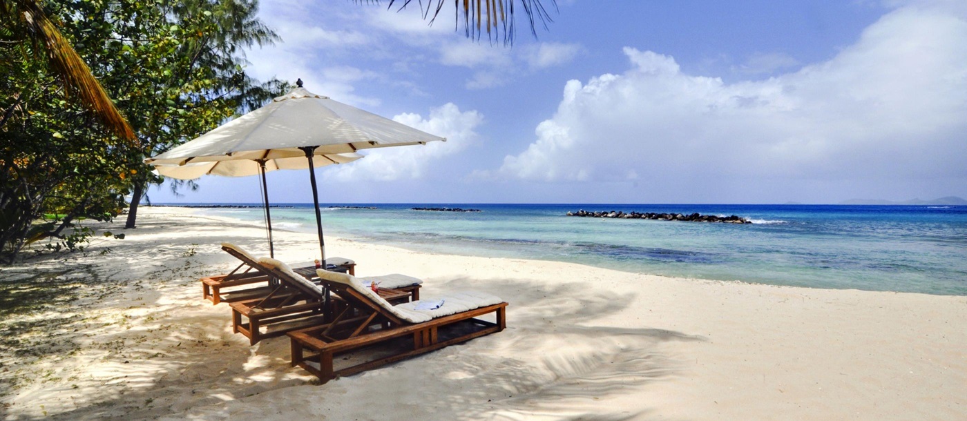 The beach and three sun loungers at Gingerbread, Mustique