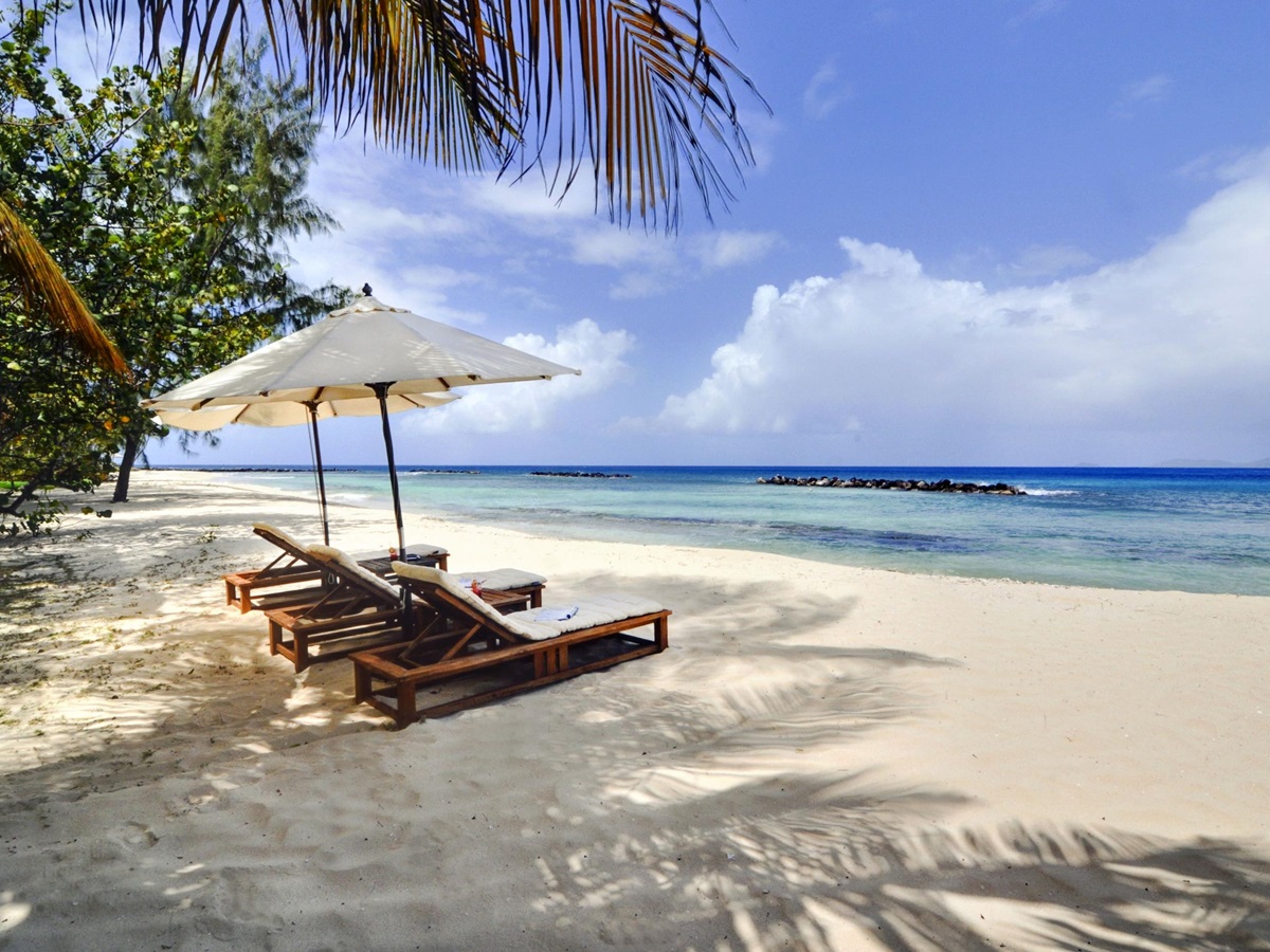 The beach and three sun loungers at Gingerbread, Mustique
