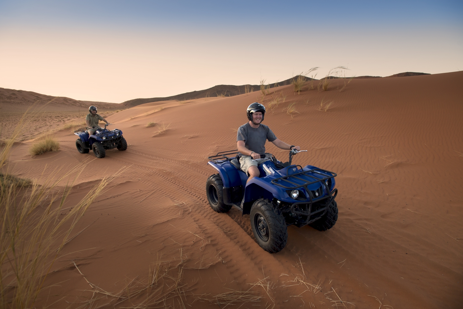 Two poeple on Quad bikes driving through the dunes