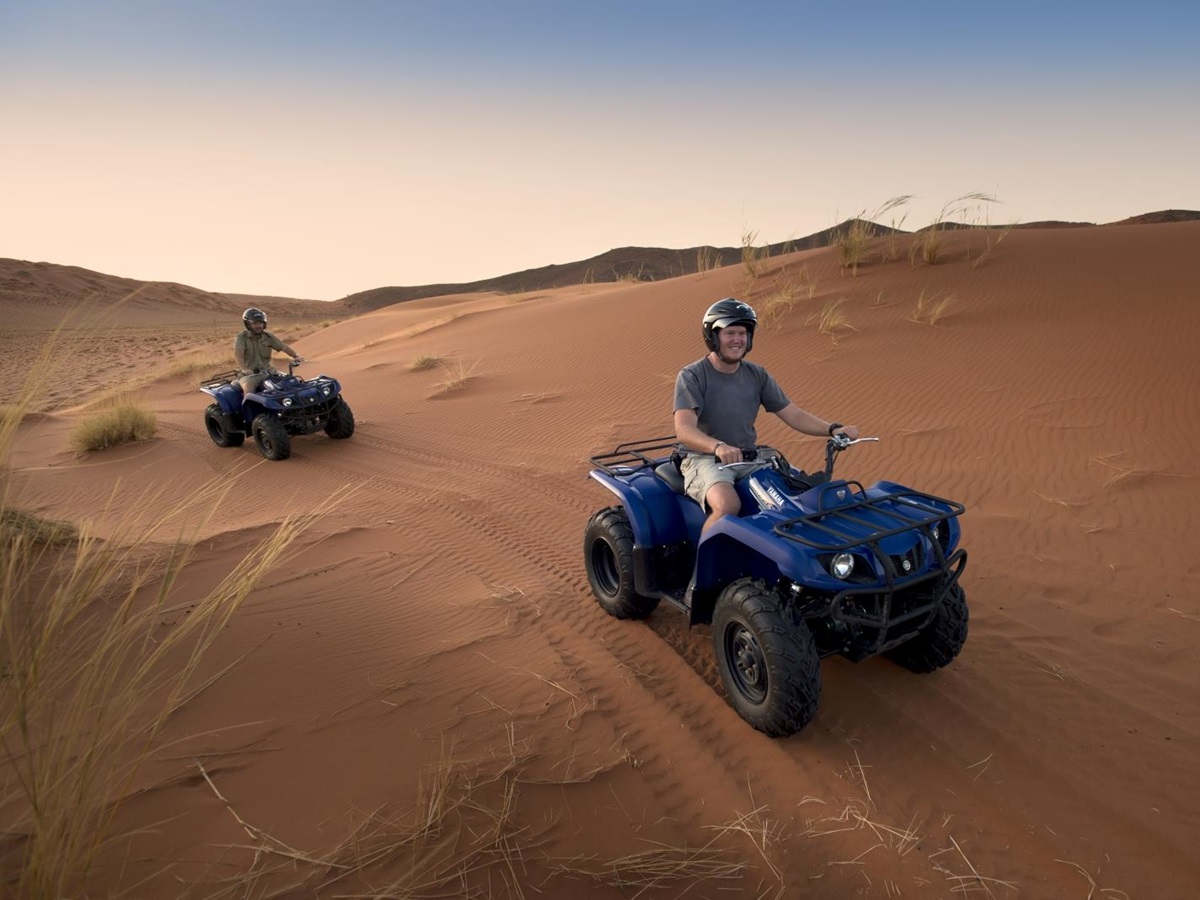 Two poeple on Quad bikes driving through the dunes