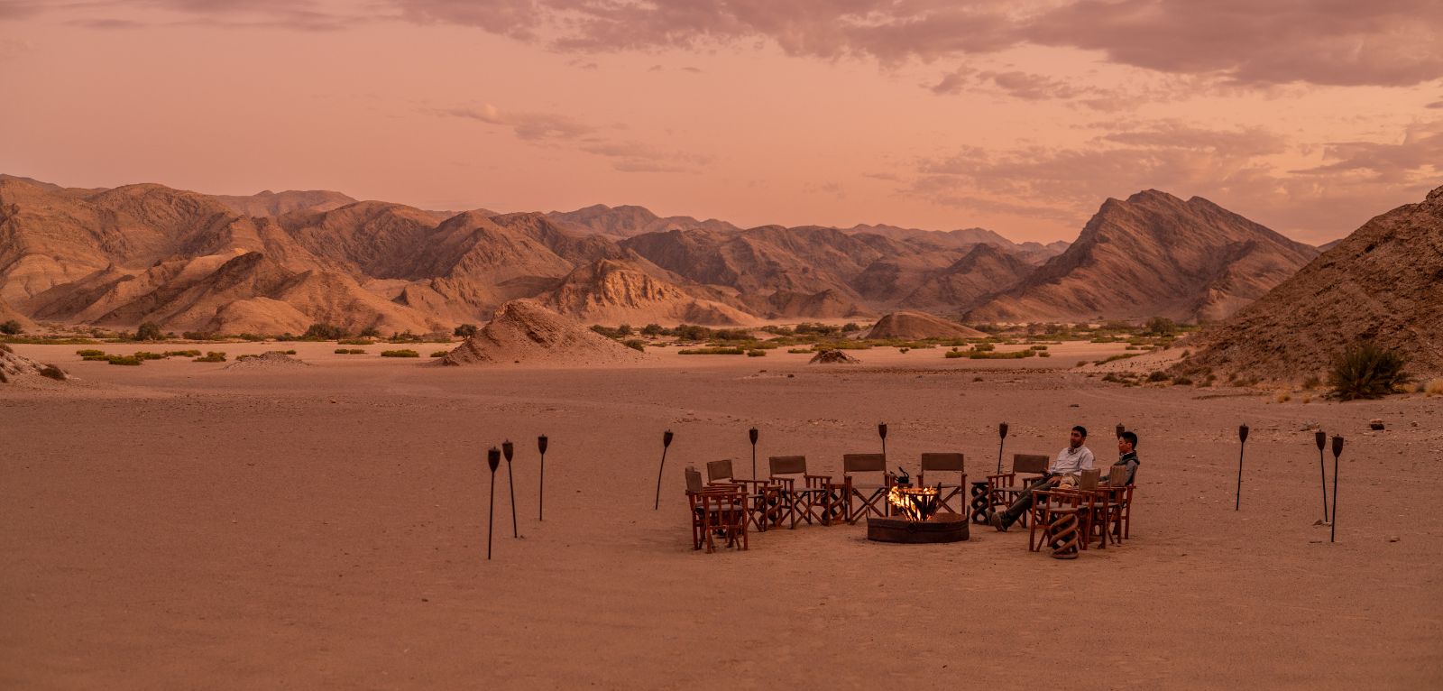 Guests at the camp fire at sunset during a stay at luxury lodge Hoanib Valley Camp in Namibia