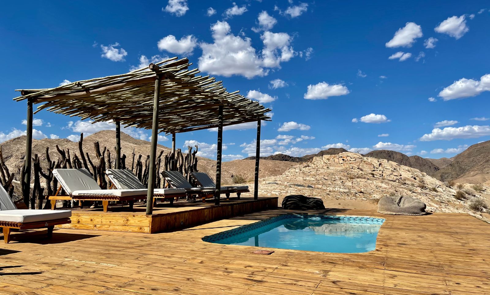 Raised swimming pool with shaded sun loungers at luxury lodge Hoanib Valley Camp in Namibia