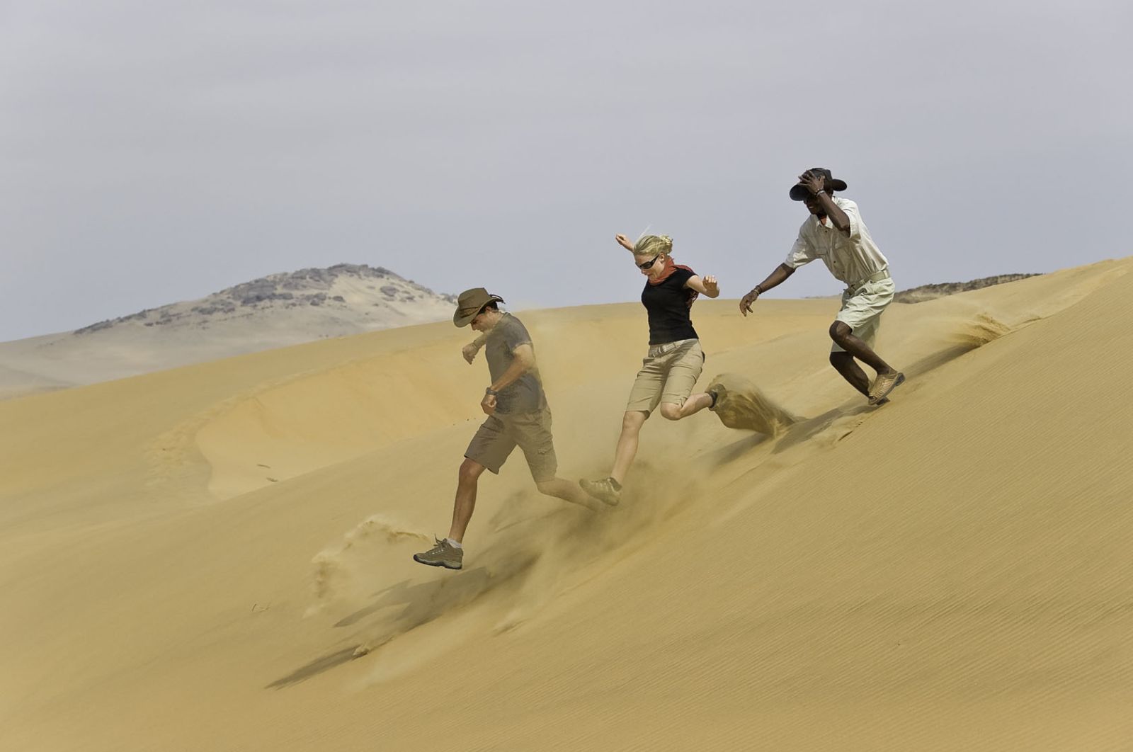 Guests running down a dune during a stay at luxury lodge Serra Cafema in Kakaoland, Namibia