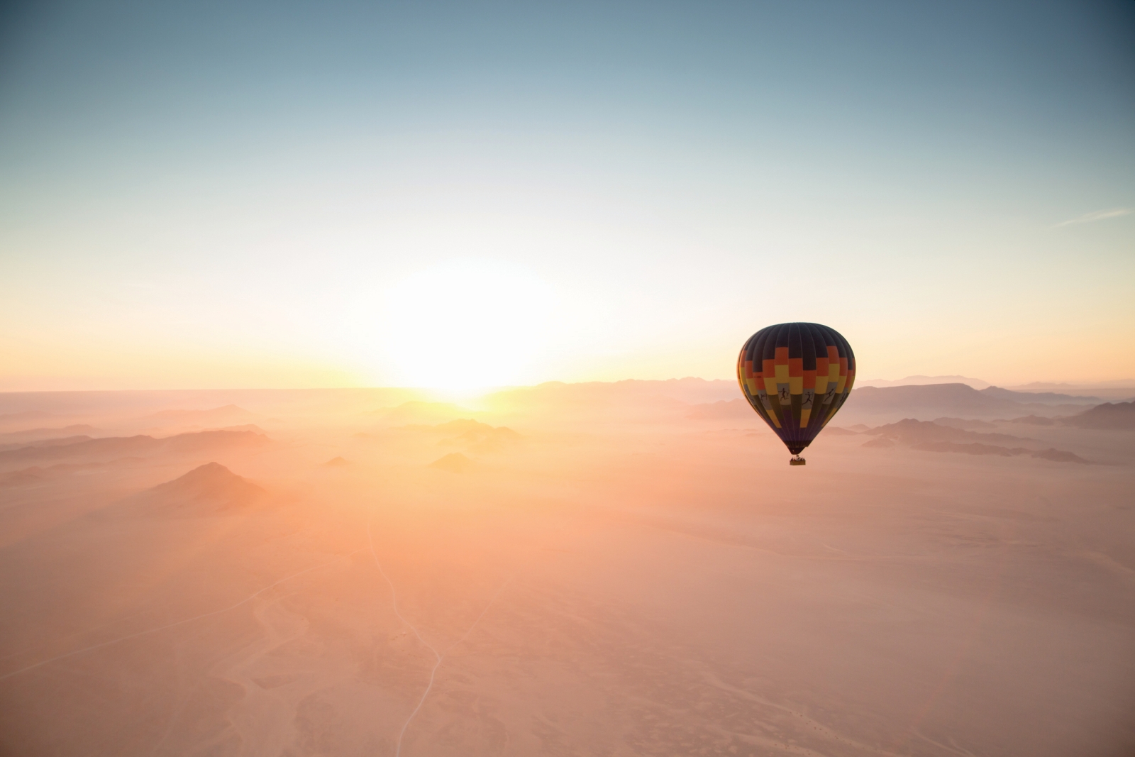Hot air balloon over the misty desert at sunrise