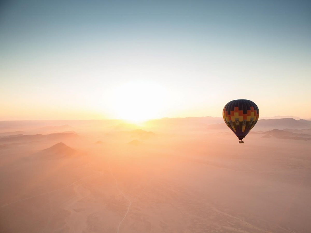Hot air balloon over the misty desert at sunrise