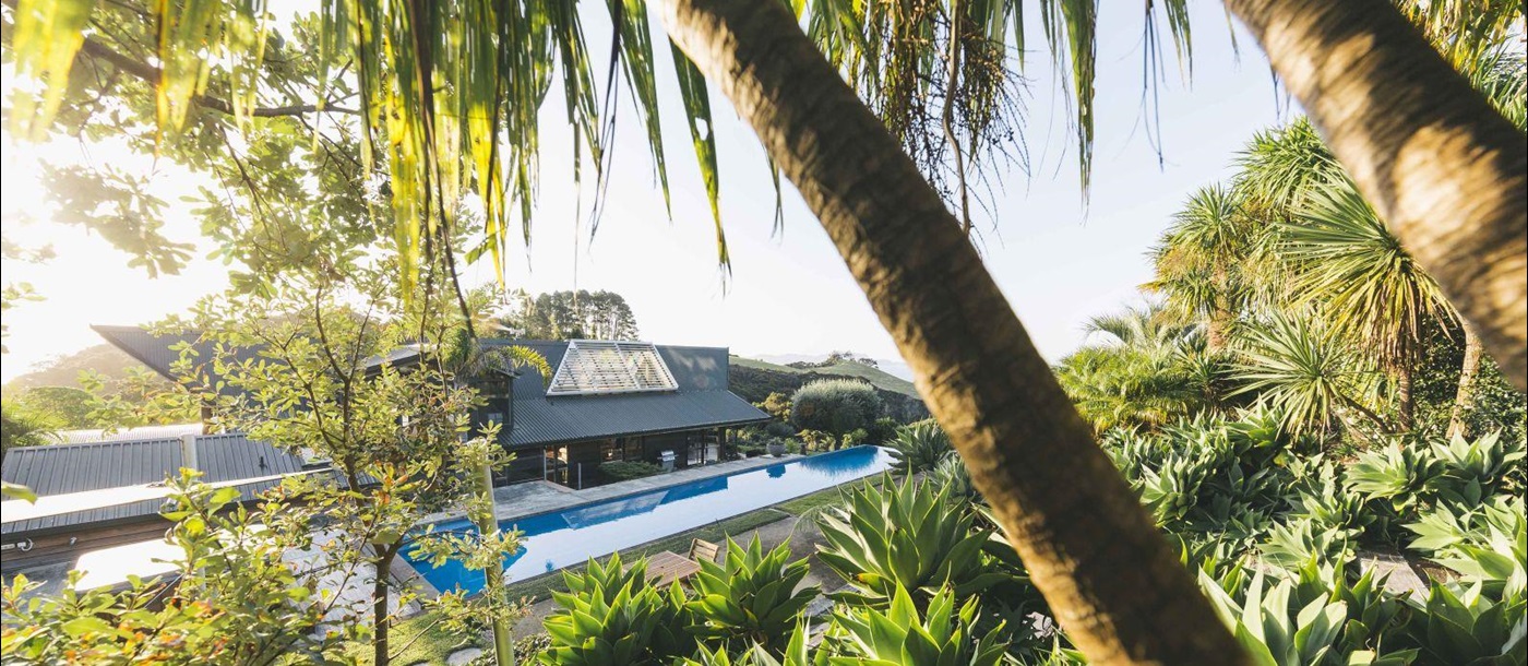 Sacred Space villa New Zealand exterior with palm trees and a pool