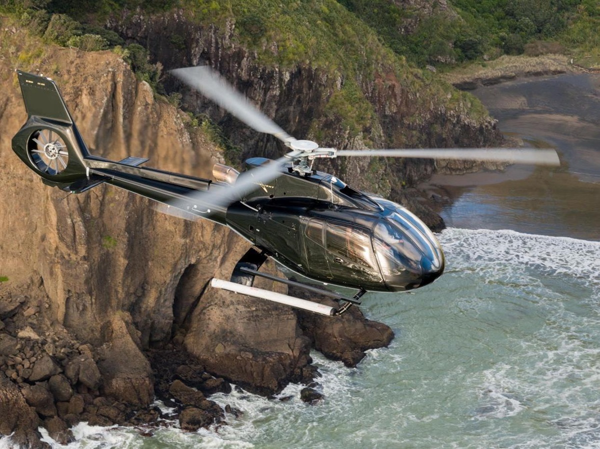 The Landing New Zealand helicopter flying over the cliffs and bay