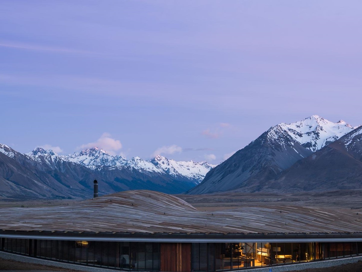 Exterior shot of the sweeping roof that blends in with the mountains in the background of The Lindis Lodge in New Zealand
