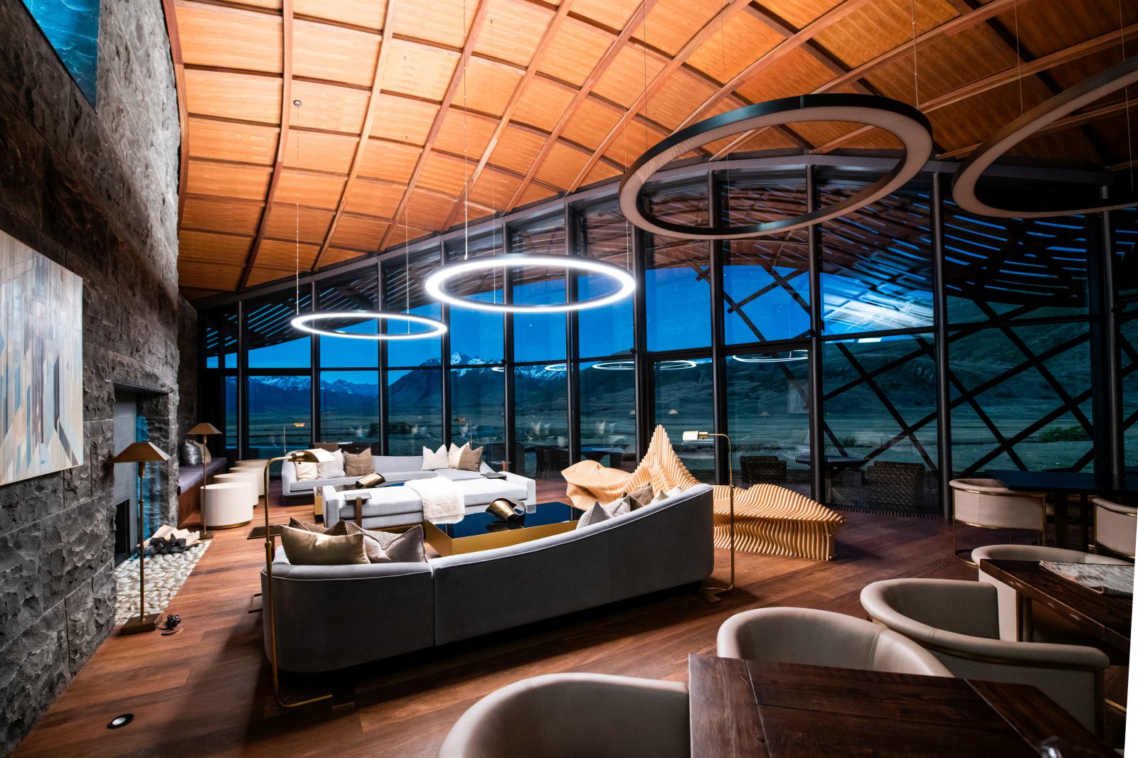 The interior of The Lindis Lodge in New Zealand with floor to ceiling windows looking out on the mountains