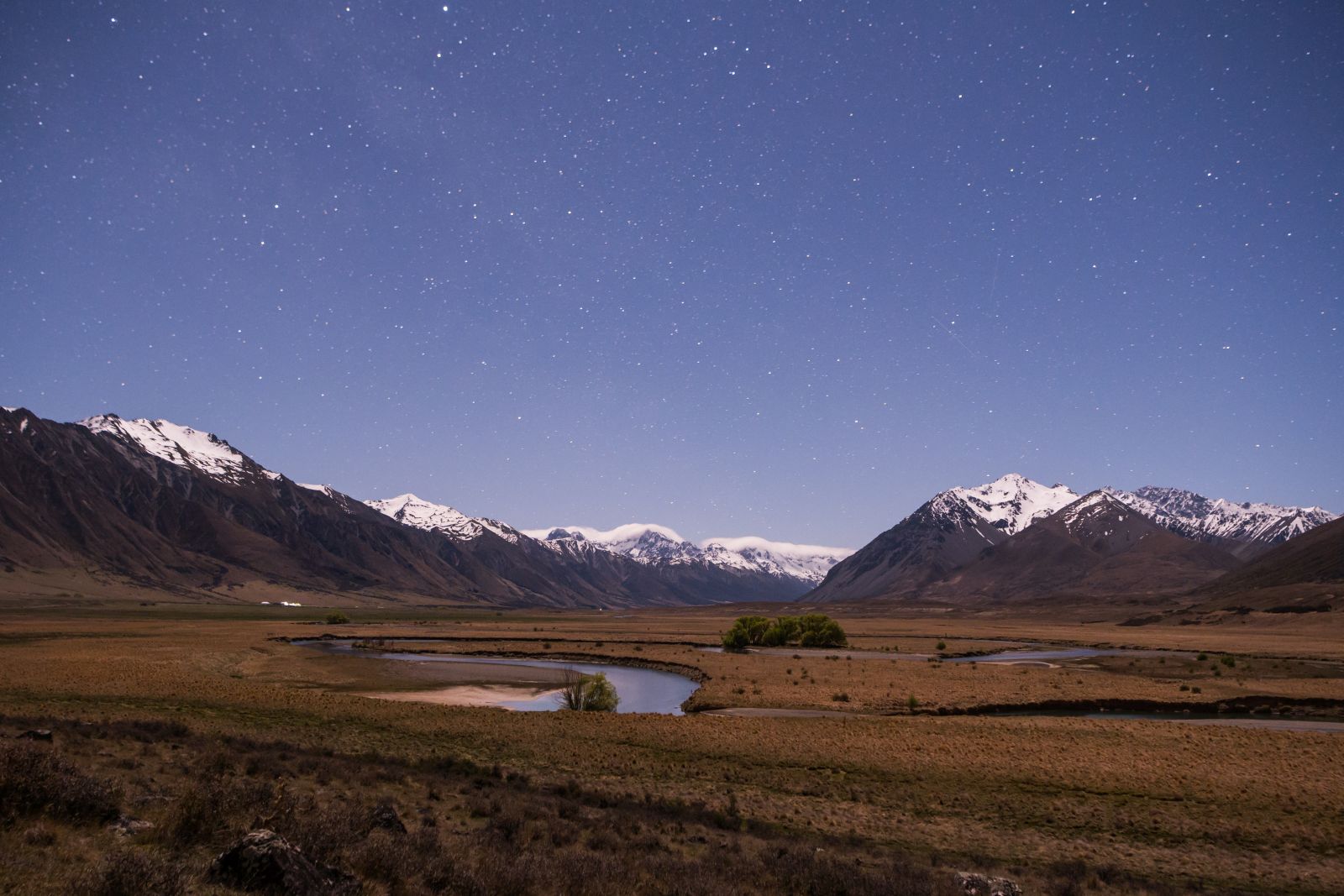 The sky at dusk above snow-capped mountains with hundreds of stars twinkling at The Lindis Lodge in New Zealand