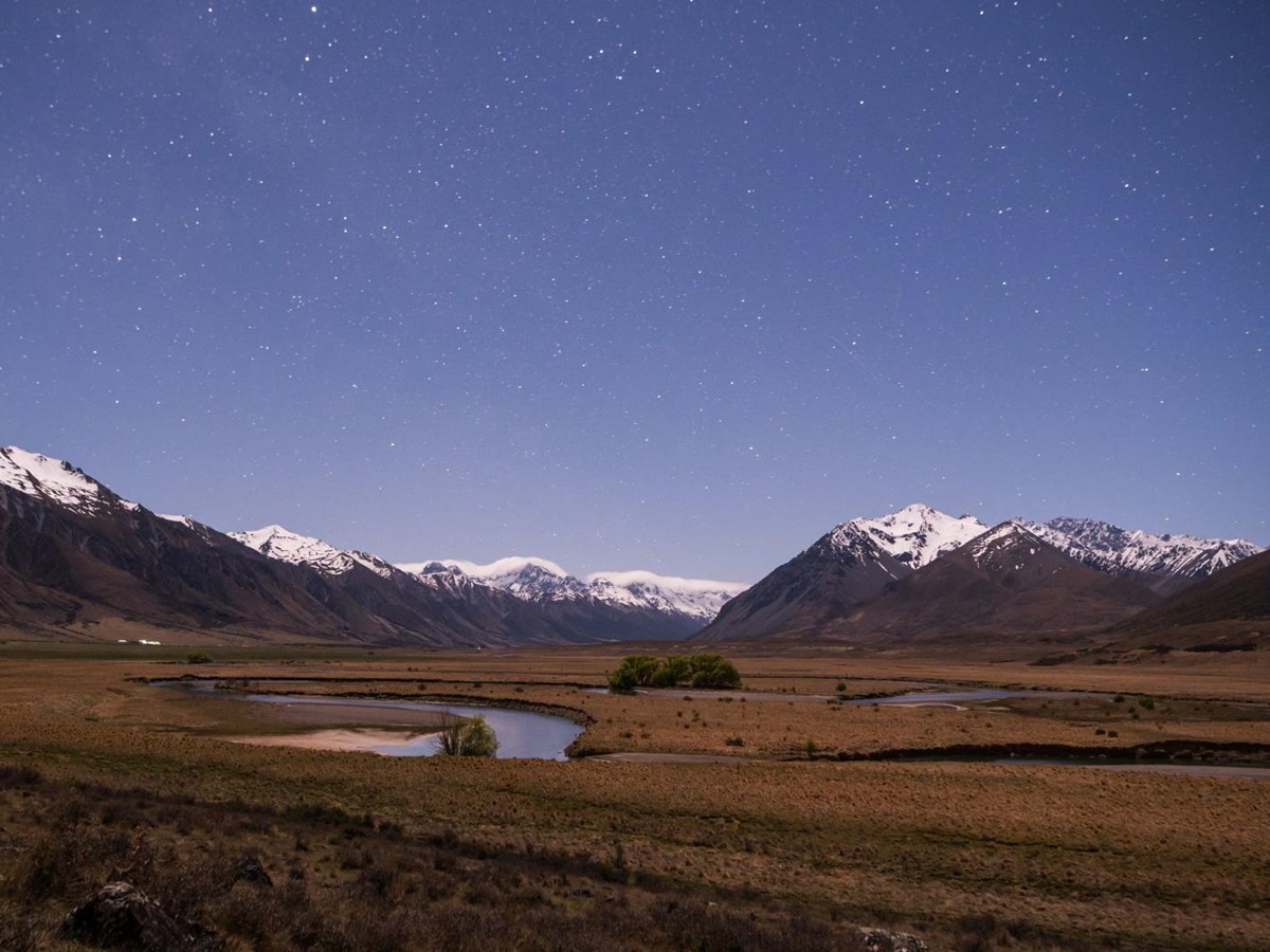 The sky at dusk above snow-capped mountains with hundreds of stars twinkling at The Lindis Lodge in New Zealand