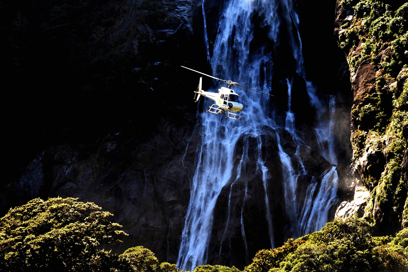 Helicopter over Milford Sound waterfall, New Zealand