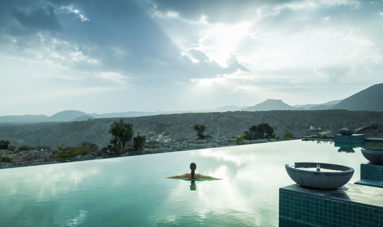 A lady in the infinity pool looking at the view of the mountains at the Anantara Al Jabal Al Akhdar Resort in Oman